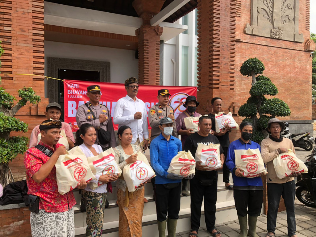 BERLANGSUNG KEGIATAN PENYERAHAN BANTUAN OLEH BAPAK KAPOLSEK MENGWI DAN BAPAK PERBEKEL DESA MENGWITANI KEPADA MASYARAKAT DALAM RANGKA HUT BHAYANGKARA